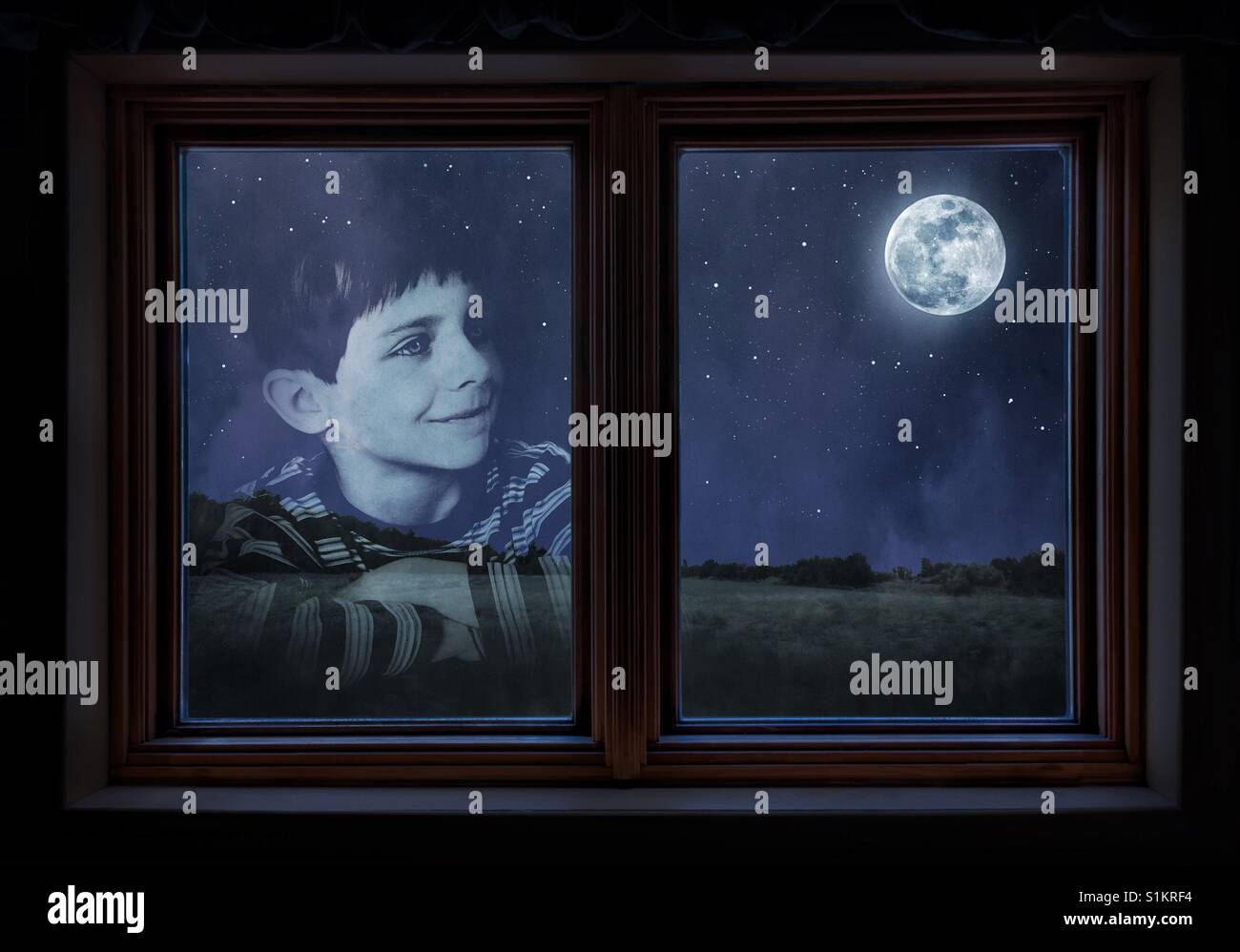 Window reflection of a young boy staring at the moon Stock Photo