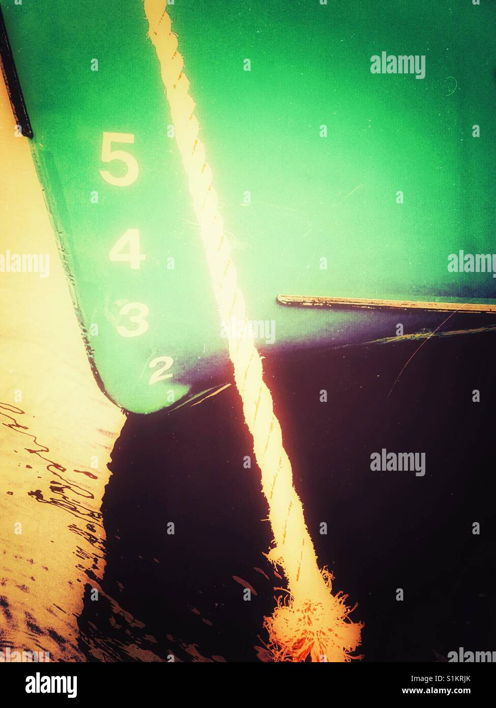 Ship's draft on green hull of moored ship. The vertical distance between the waterline and the bottom of the hull. - Smartphone Captured Stock Image