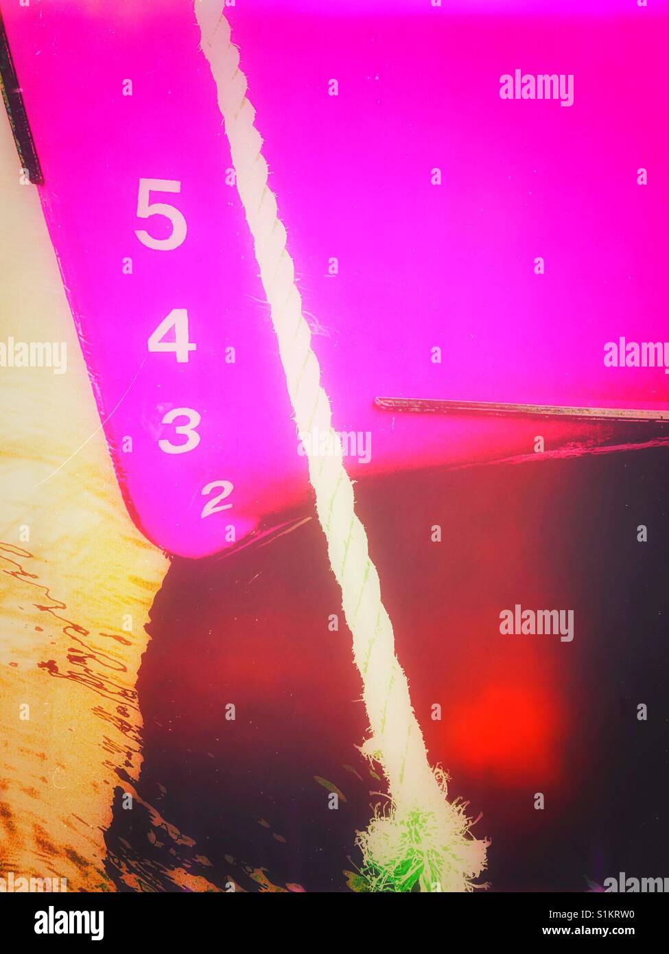 Ship's draft on pink hull of moored ship. The vertical distance between the waterline and the bottom of the hull. - Smartphone Captured Stock Image