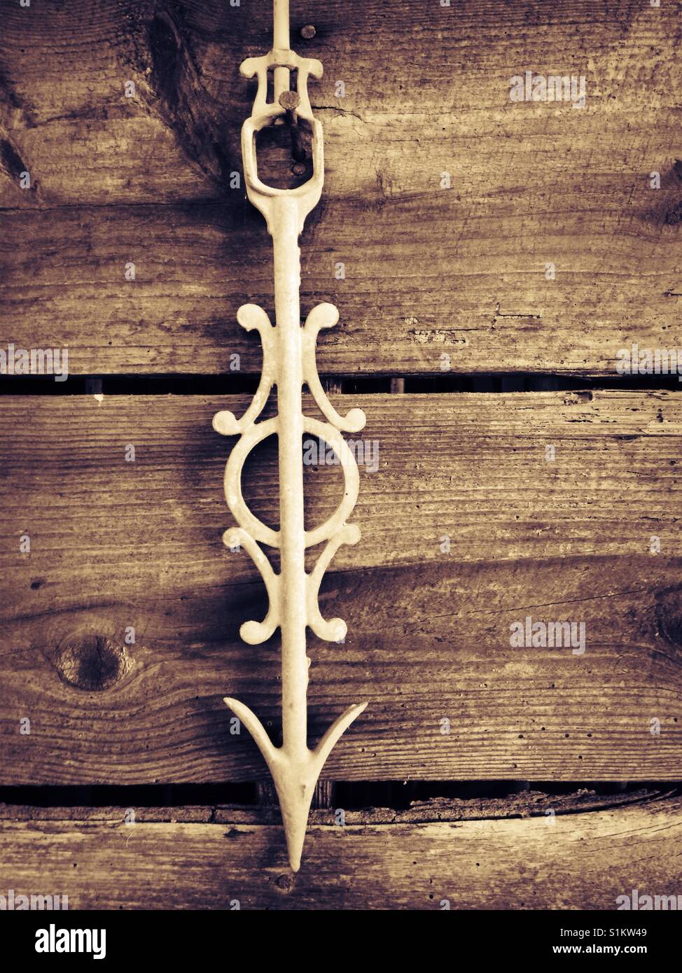 Which direction? Old white cast iron weather vane arrow hangs on wooden shed wall - Smartphone Captured Stock Image