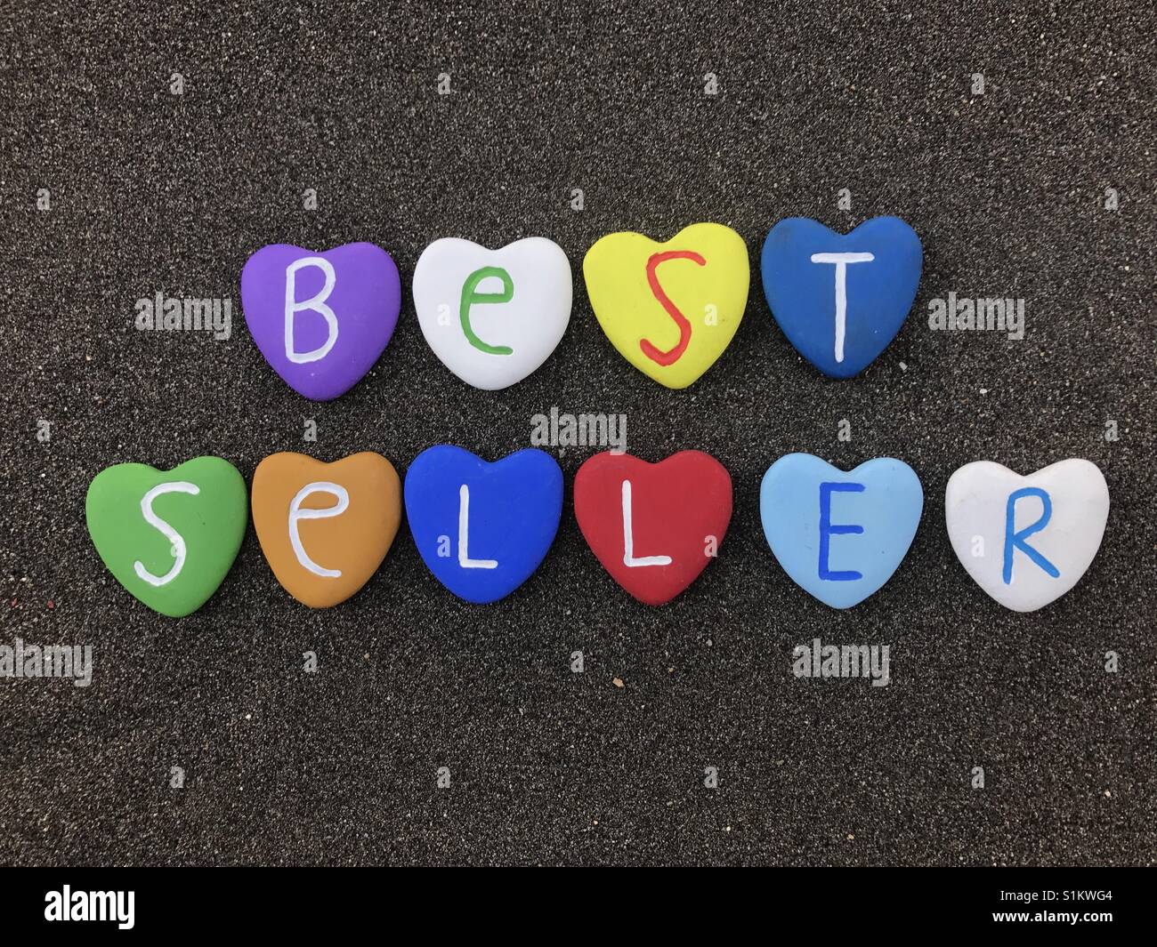 Best seller, colored heart stones over black volcanic sand - Smartphone Captured Stock Image