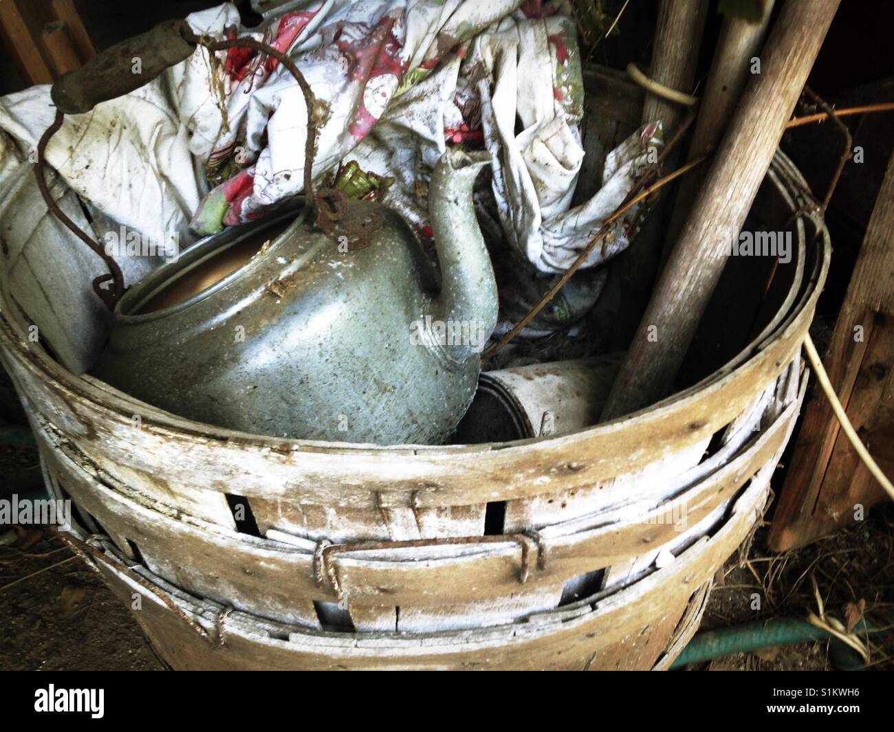 Metal teakettle, barkcloth curtain, wooden handled inside stack of bushel baskets Stock Photo
