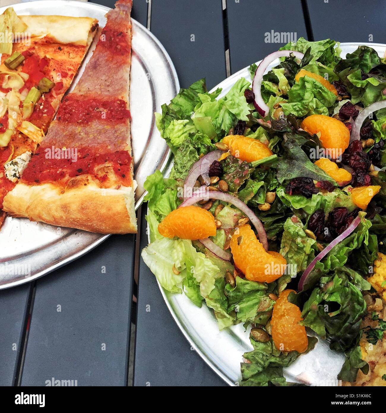 Vegan pizza slices and fresh salad on the table in Sizzle Pie restaurant in Seattle Stock Photo