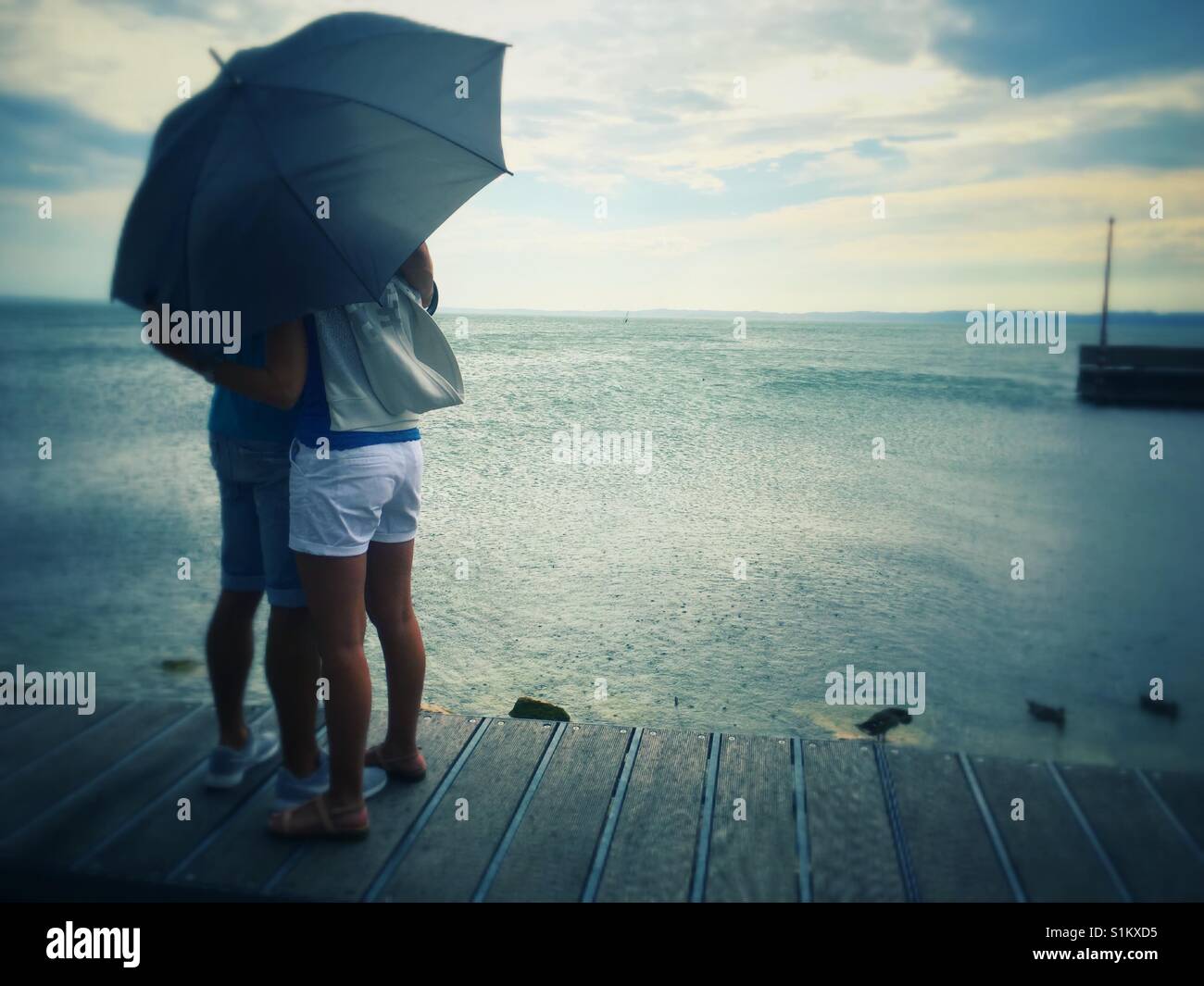 Couple at seaside with umbrella Stock Photo