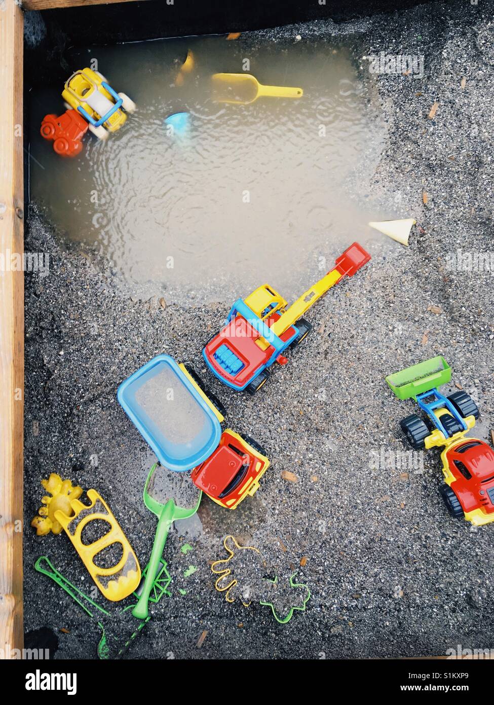 Lonely toys in the sand during a rainfall Stock Photo
