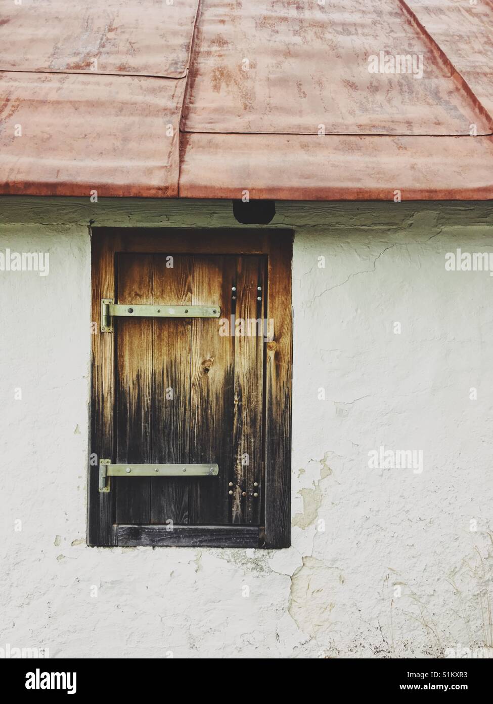 Closed wooden window in a white wall and red roof - Smartphone Captured Stock Image