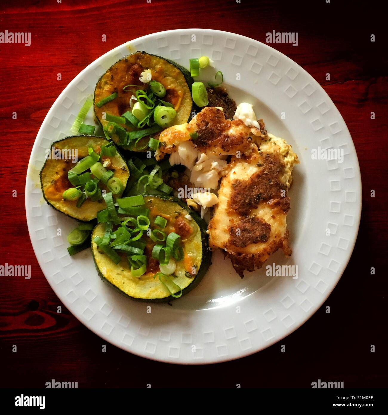 Fried fish with zucchinis and green onion on a side on the white plate. - Smartphone Captured Stock Image