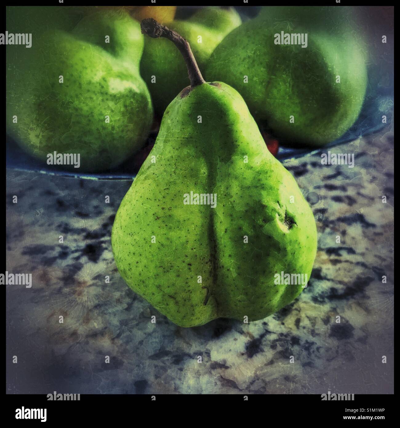 Pear on table with fruit on plate in background. Stock Photo