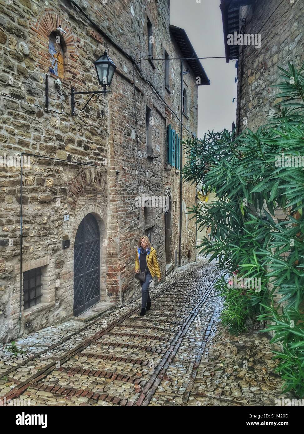 Woman walking down a cobblestone road in Umbria, Italy. Stock Photo