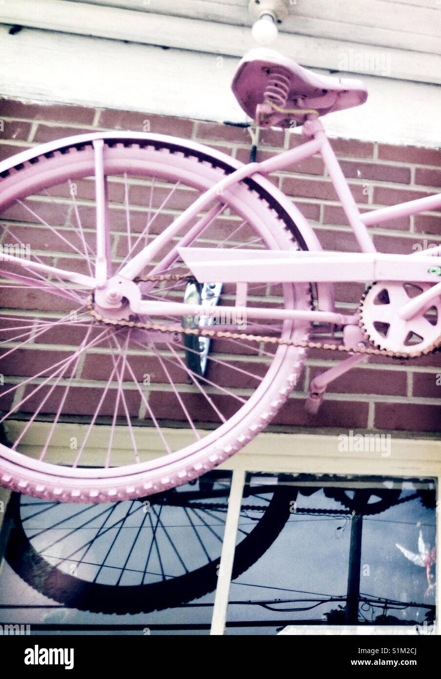 Back wheel of pink tandem bike on display above shop window - Smartphone Captured Stock Image