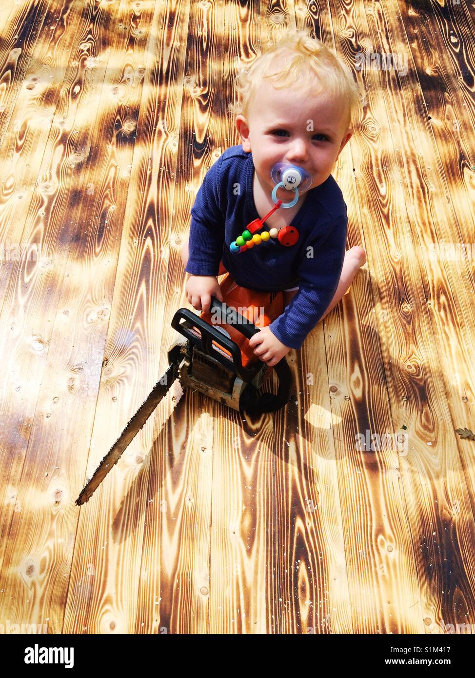 Baby boy with a toy chainsaw - Smartphone Captured Stock Image