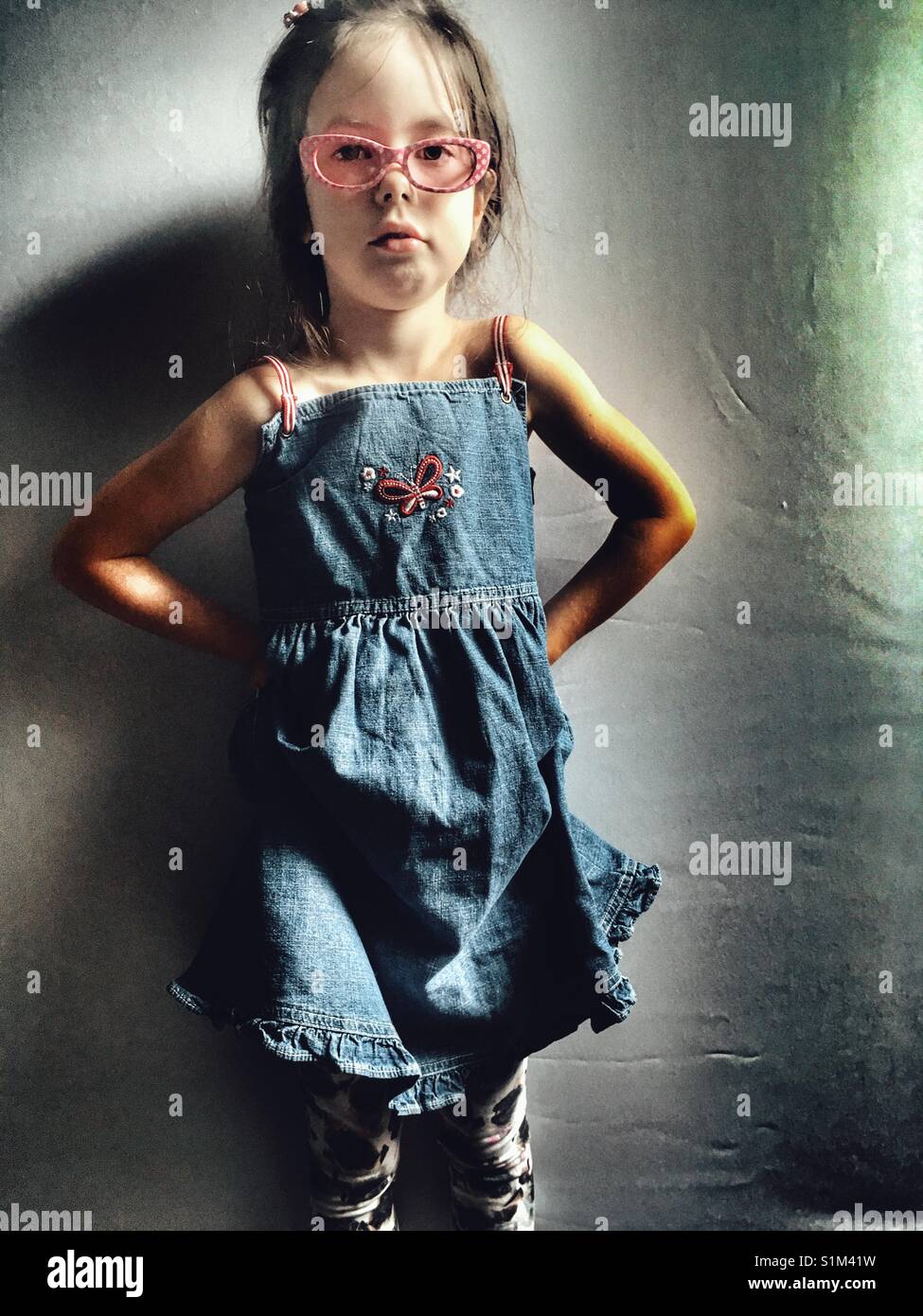 Girl wearing denim dress and leggings Stock Photo
