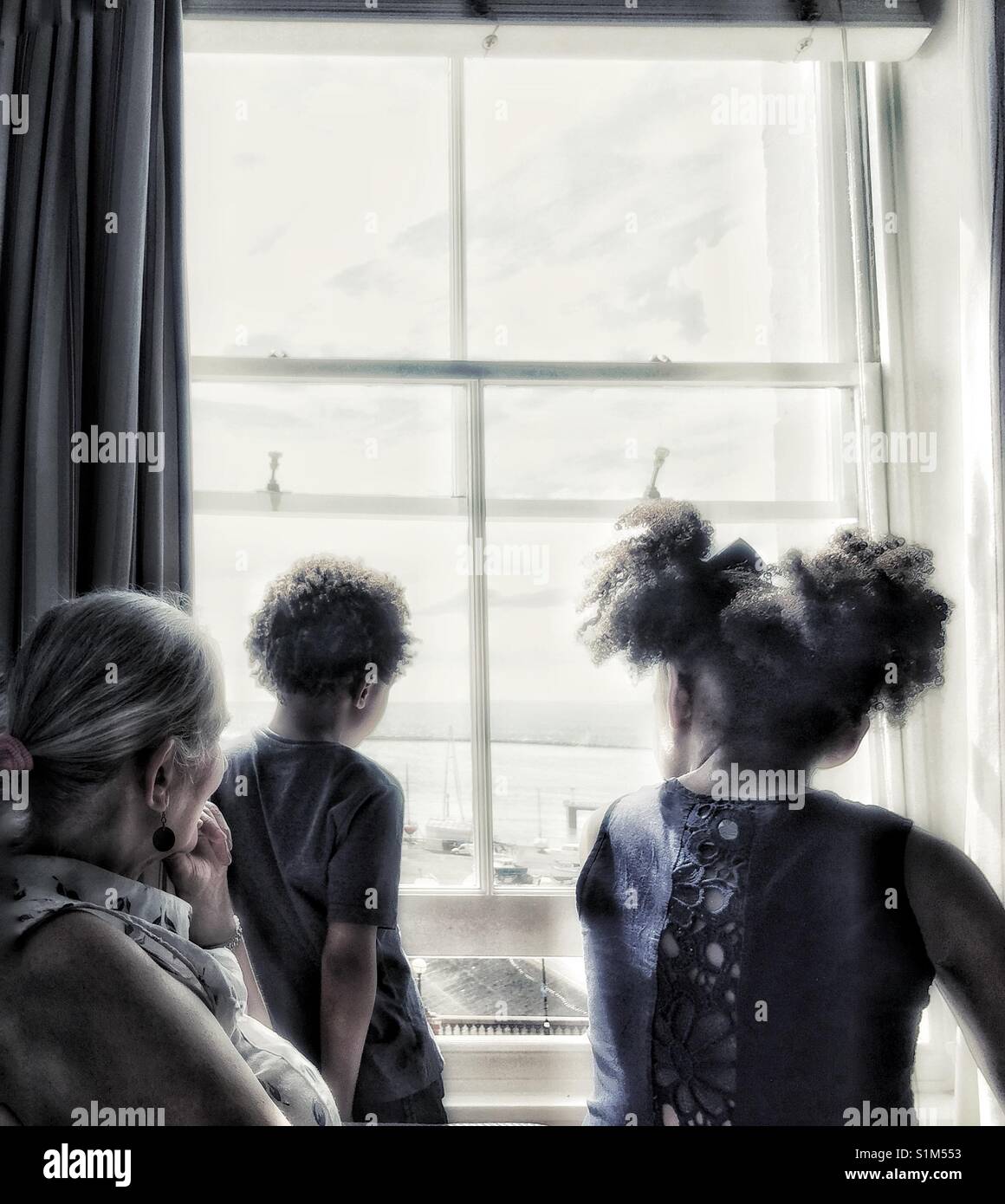 A family gazing out of a window. - Smartphone Captured Stock Image