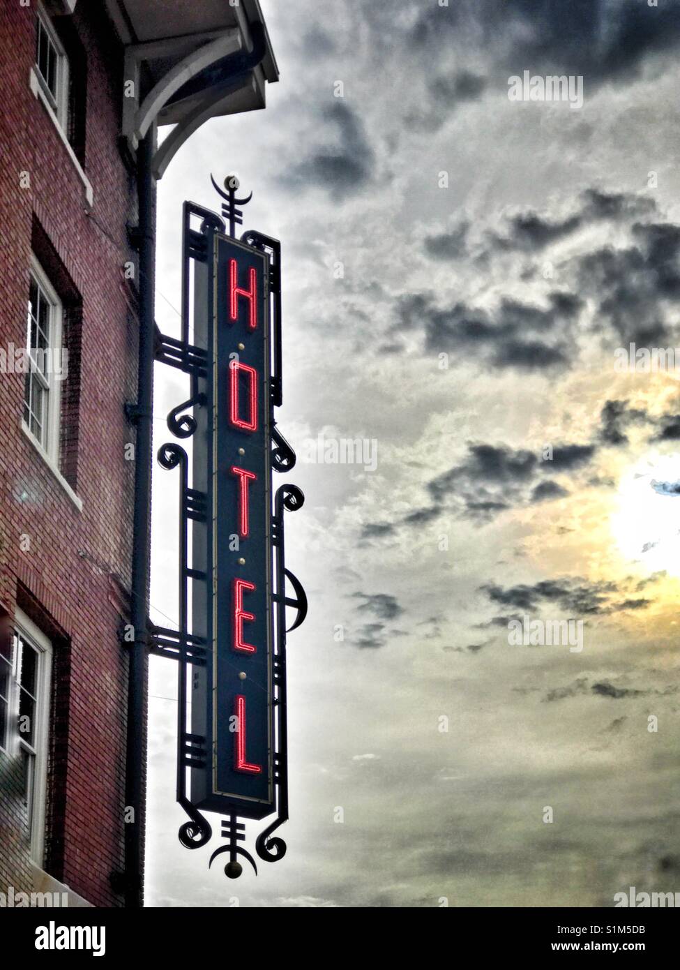 Hotel sign hanging on a historic brick building against a dramatic cloudy morning sky - Smartphone Captured Stock Image Hotel sign hanging on a historic brick building against a dramatic cloudy morning sky - Smartphone Captured Stock Image