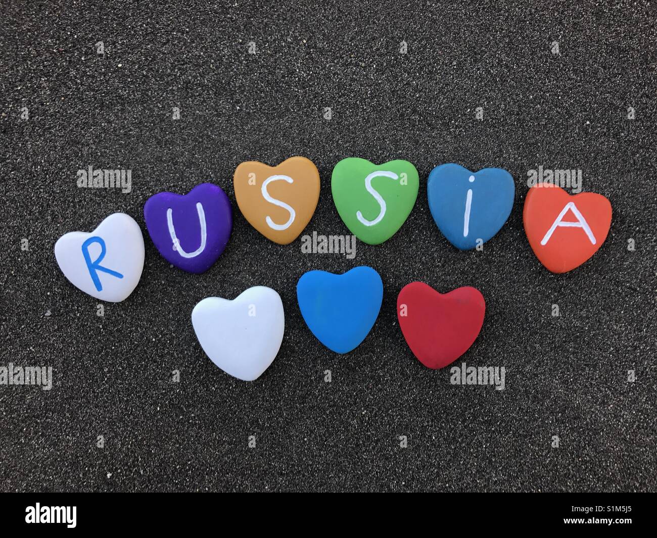 Russia, country name with colored hearts stones over black volcanic sand - Smartphone Captured Stock Image