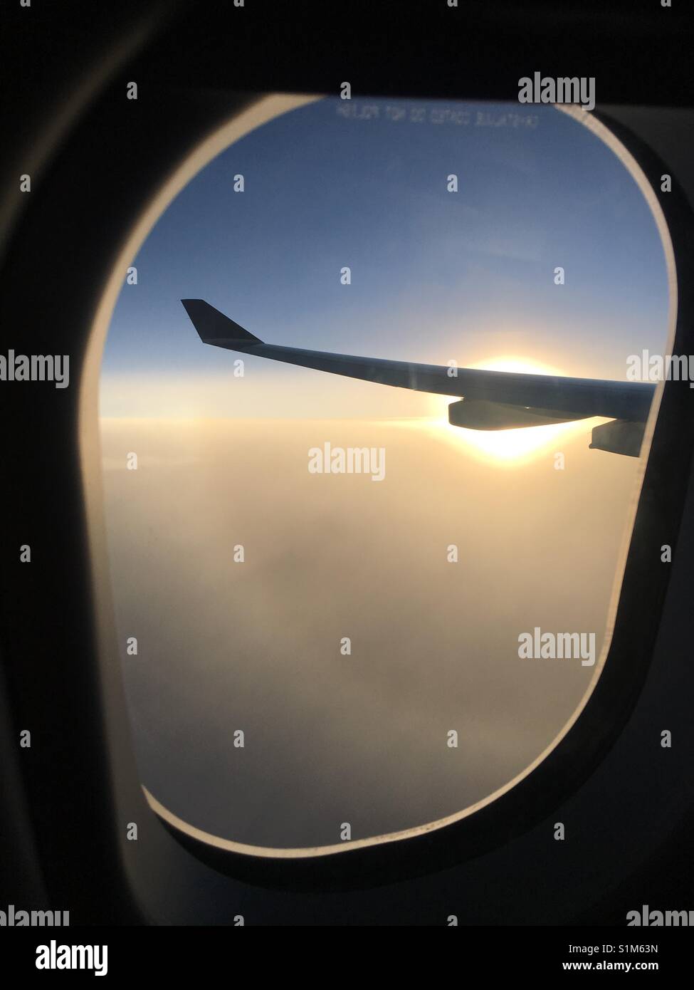 View of a plane wing through a window during sunset Stock Photo