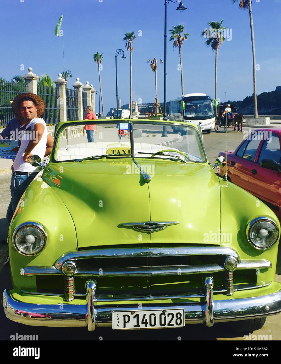 A Cuban man standing by his colorful 1950's convertible Chevrolet car in Havana, Cuba. Stock Photo