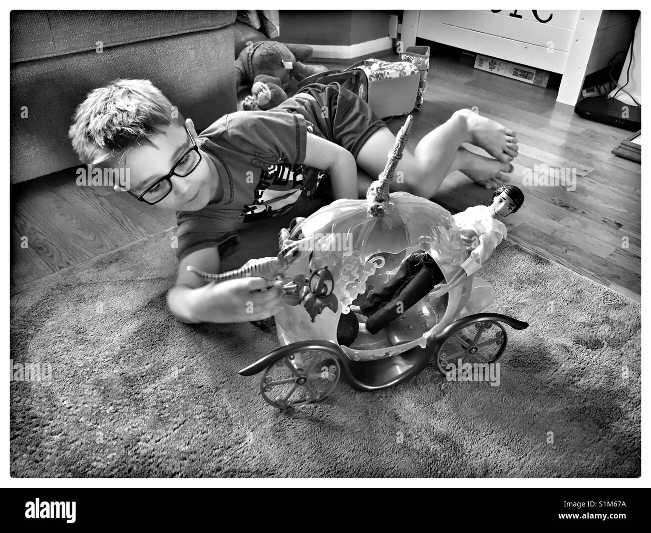 Non gender stereotypes, boy playing with Barbie toys. Stock Photo