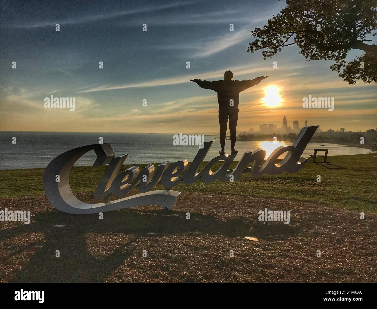 Young woman standing on Cleveland sign with outstretched arms - Smartphone Captured Stock Image