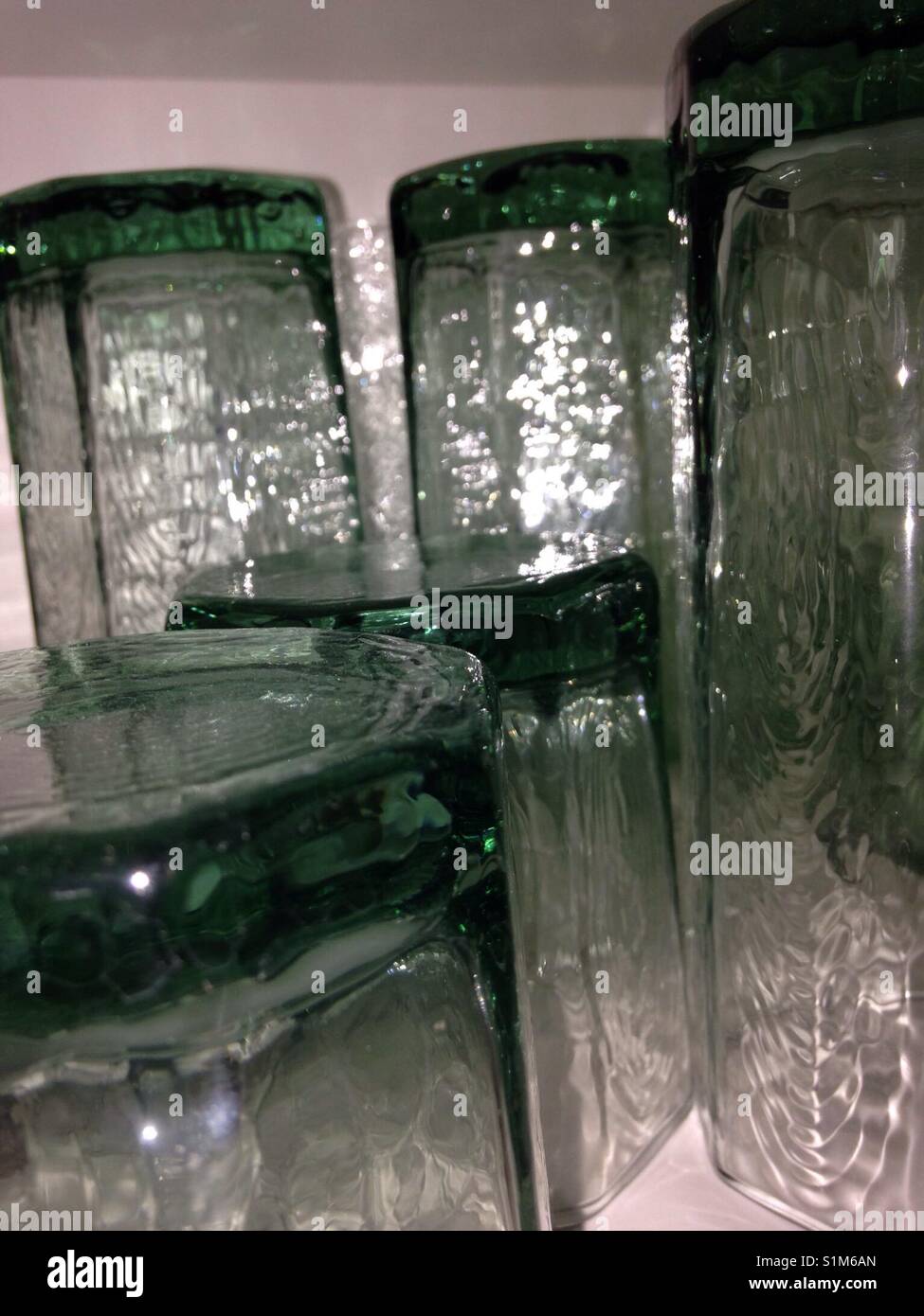 Green drinking glasses in a cabinet. Textured surfaces. Stock Photo