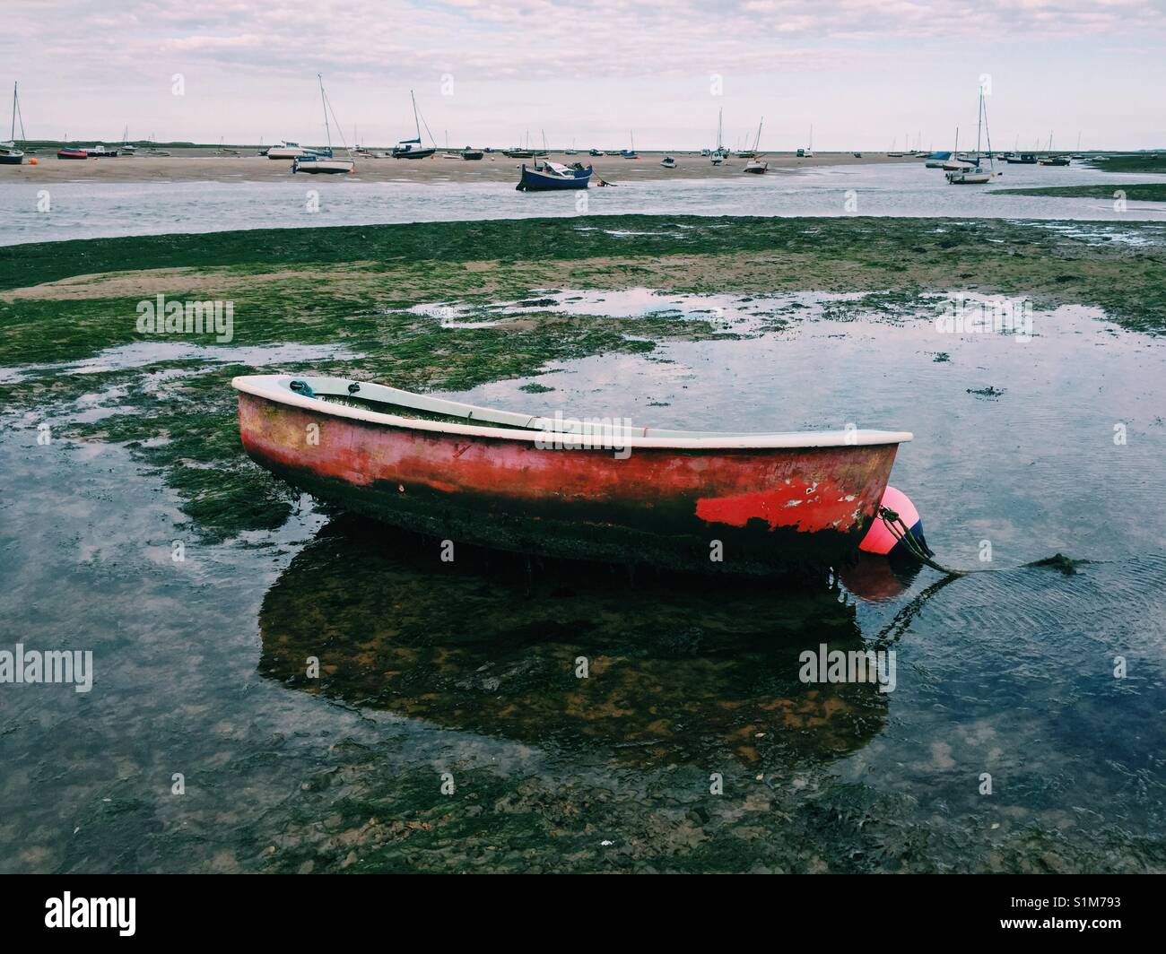 Red bottomed boat in anchor at low tide, Morston beach, North Norfolk, UK - Smartphone Captured Stock Image
