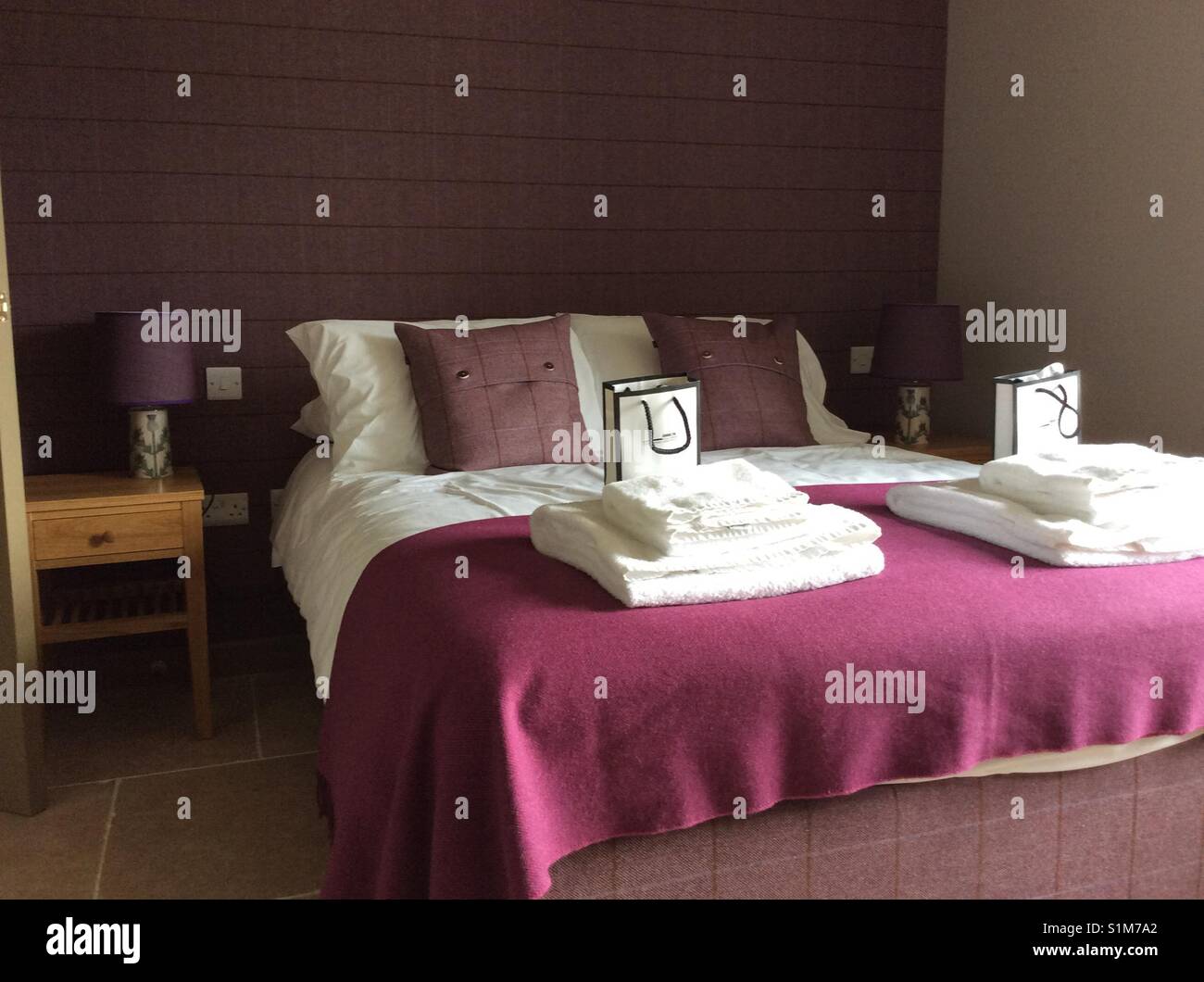 Beautiful hotel bedroom with tasteful Scottish decor of white linens and purple accessories - Smartphone Captured Stock Image