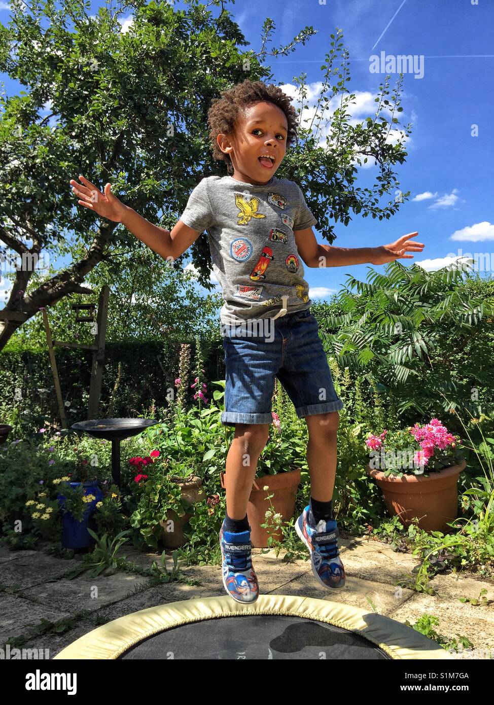 A little boy jumping on a garden trampoline Stock Photo
