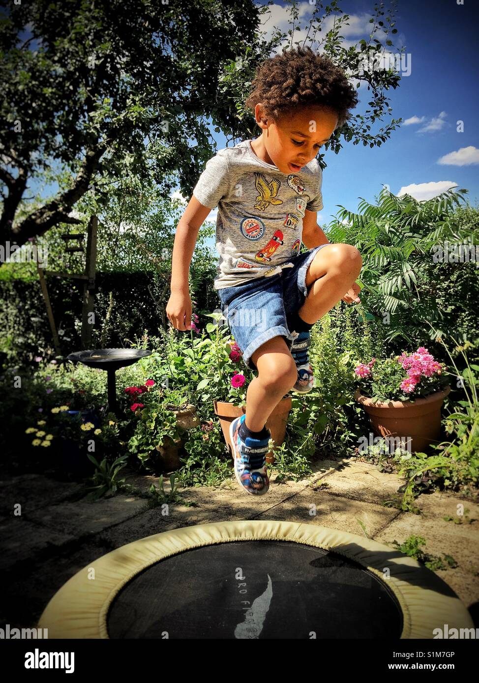 Little boy jumps on a garden trampoline Stock Photo