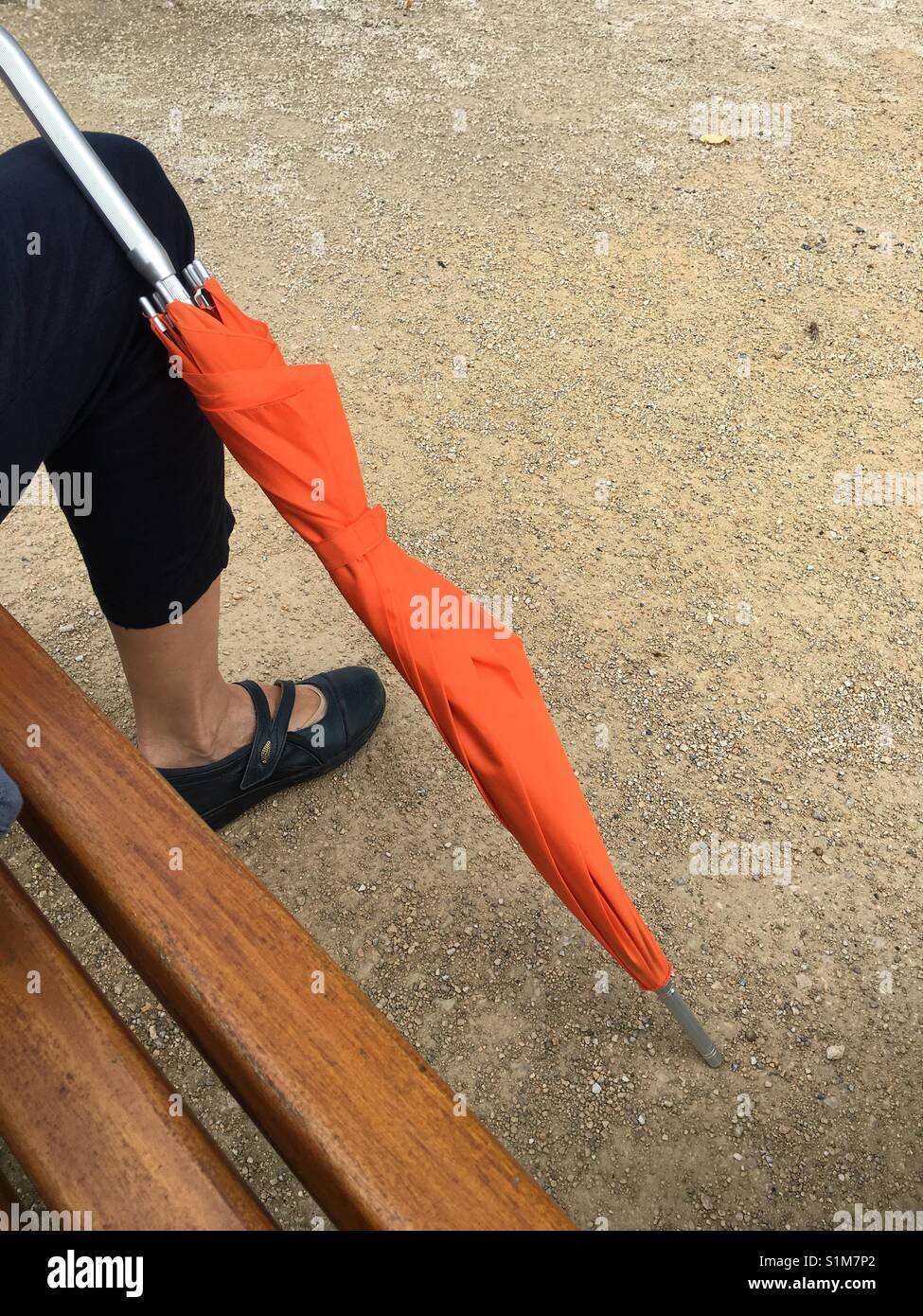 Sitting on a bench with orange umbrella on a rainy day - Smartphone Captured Stock Image