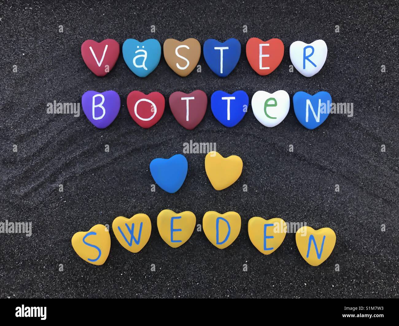 Västerbotten County, Sweden, souvenir with a composition of colored heart stones over black volcanic sand Stock Photo