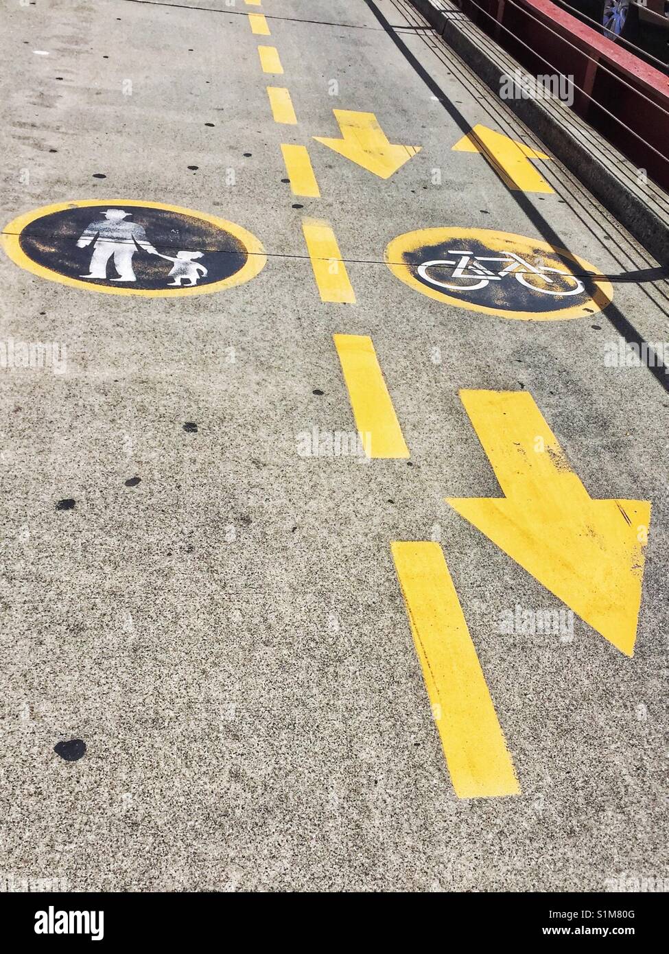 Shared pathway for bicycles and pedestrians notices painted on concrete with symbols, directional arrows and lane lines marking. Safety signage on concrete Stock Photo