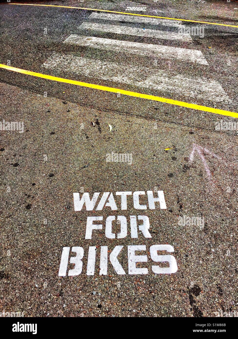 Safety notice warning pedestrians to 'watch for bikes' at crossing over bike path. Stock Photo