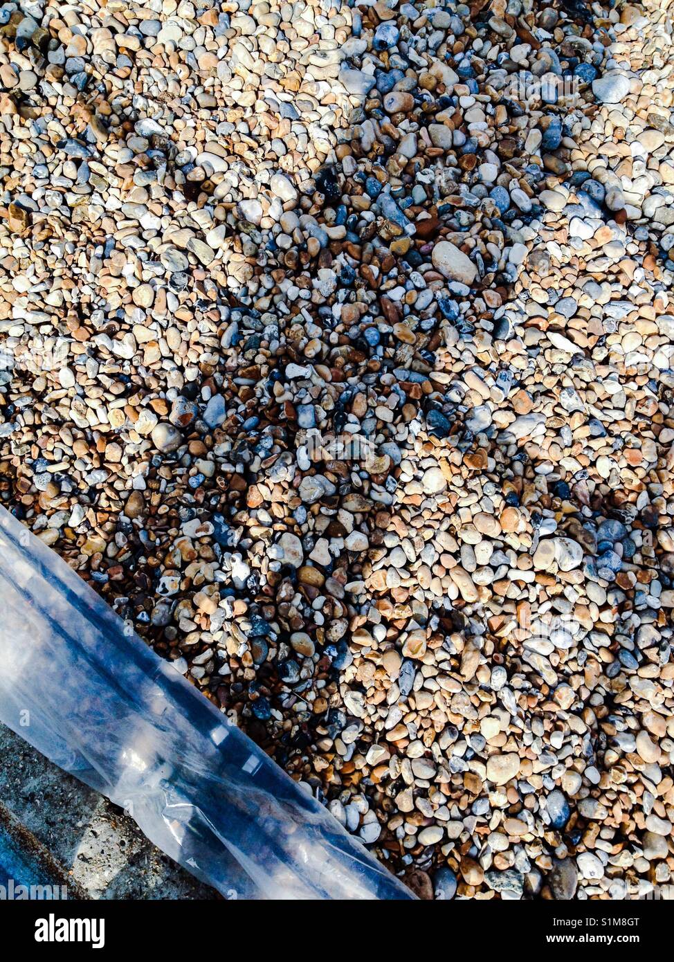 Shaddow of a man at some railings by a pebble beach - Smartphone Captured Stock Image