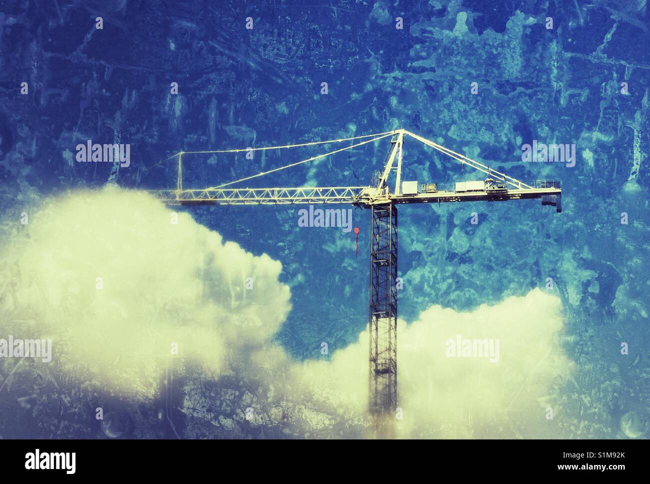 Building crane rising above the clouds. Stock Photo