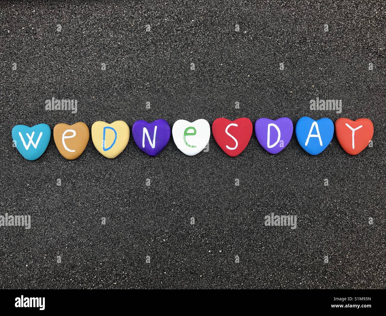 Wednesday, third day of the week with colored heart stones over black volcanic sand - Smartphone Captured Stock Image