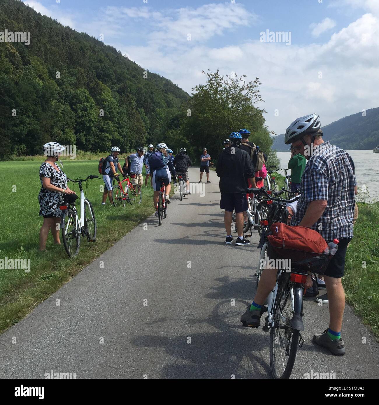 Group of casual cyclists stopped on roadside adjacent Rhine River, Germany. Stock Photo