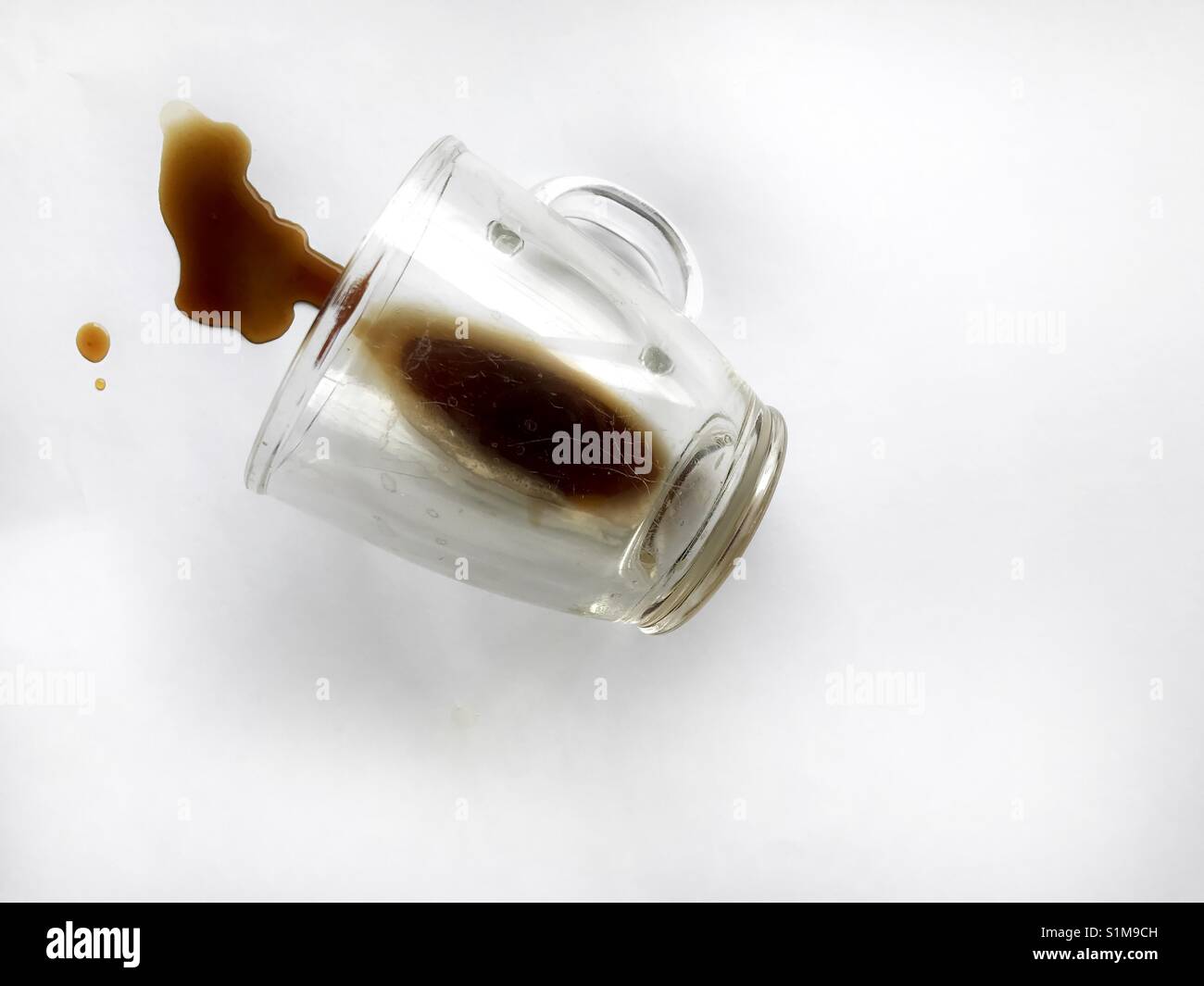 Spilled coffee from a glass cup over a white background - Smartphone Captured Stock Image
