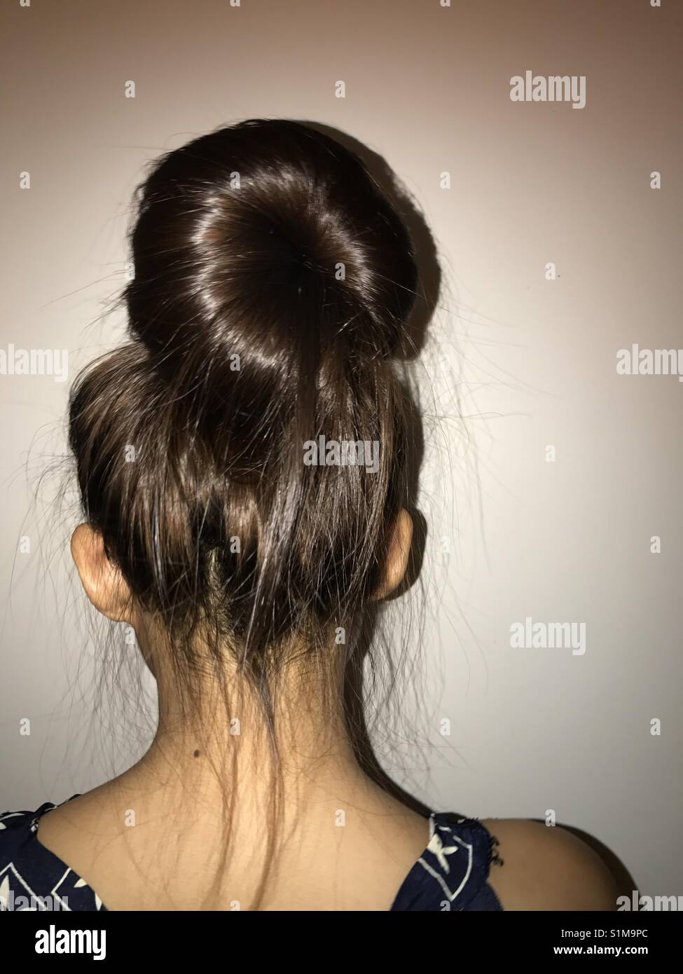 Behind the girl with a messy hair in a bun Stock Photo