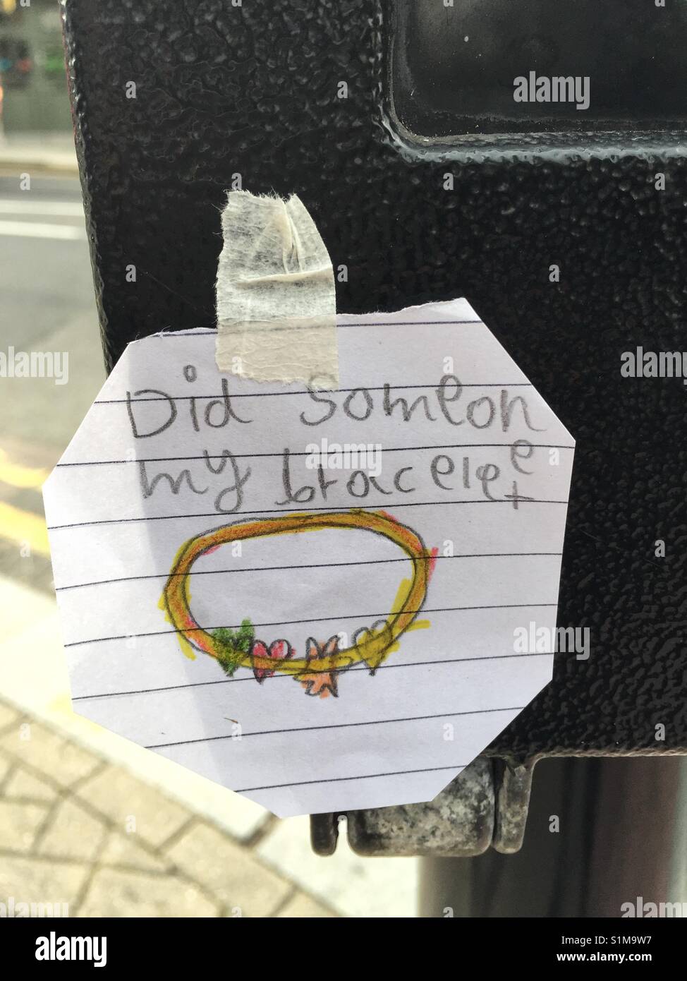 Child's note stuck onto the pedestrian crossing button - Smartphone Captured Stock Image