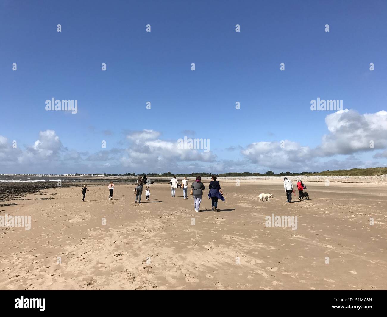 Newton Bay, Porthcawl, Wales- August 2017:  People enjoy a leisurely stroll on the quiet beach at low tide - Smartphone Captured Stock Image