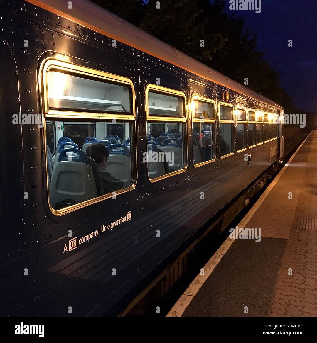 Cardiff Bay, Cardiff, Wales - 2016: A late train with passengers on board about to depart a deserted station on its shuttle trip to the city centre - Smartphone Captured Stock Image