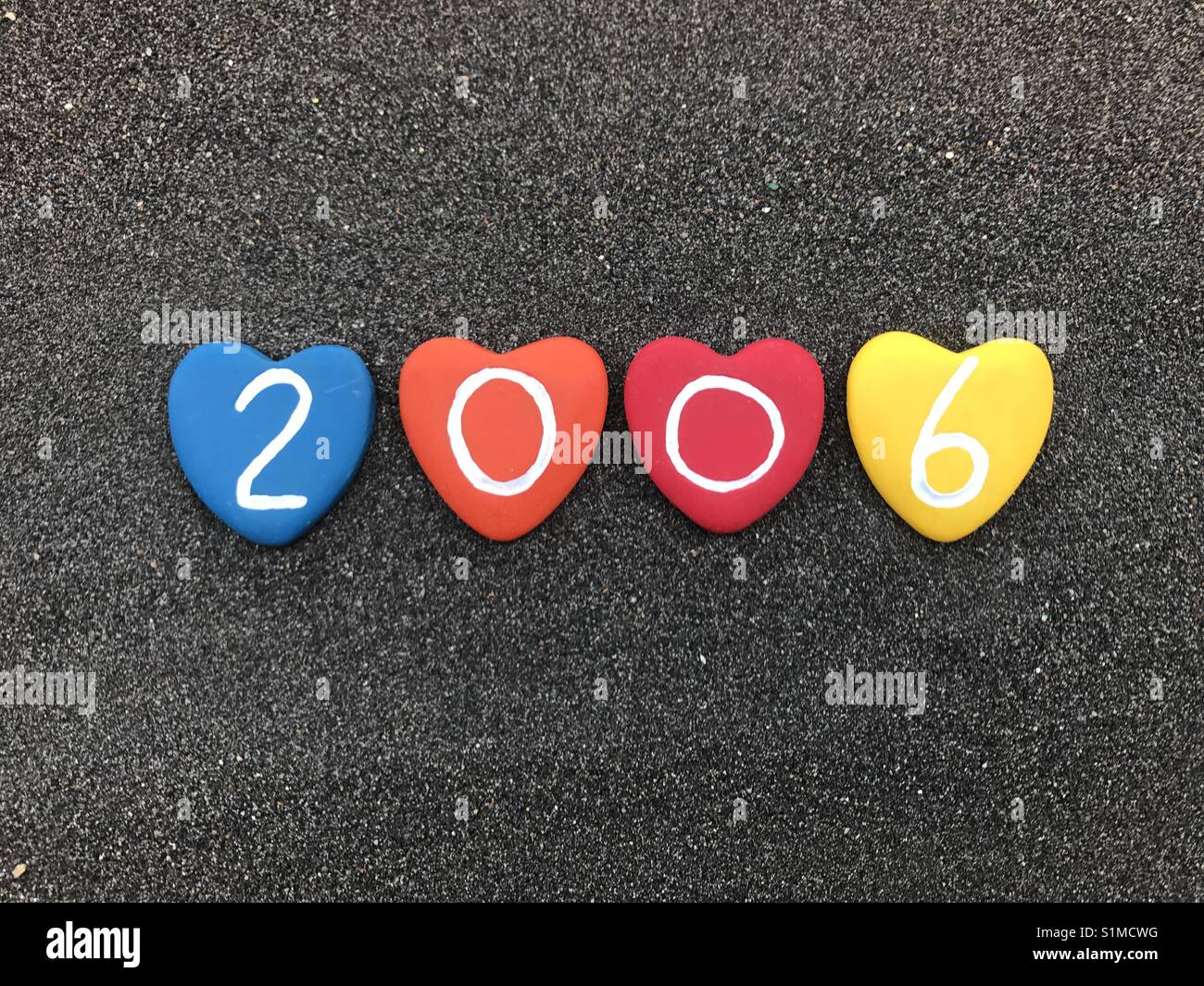 2006 year with colored heart stones over black volcanic sand - Smartphone Captured Stock Image