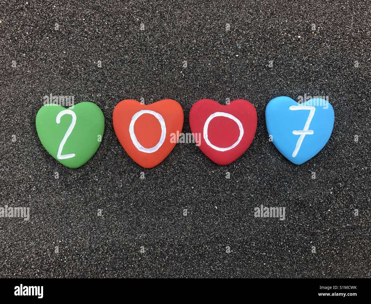 2007 year with colored heart stones over black volcanic sand - Smartphone Captured Stock Image