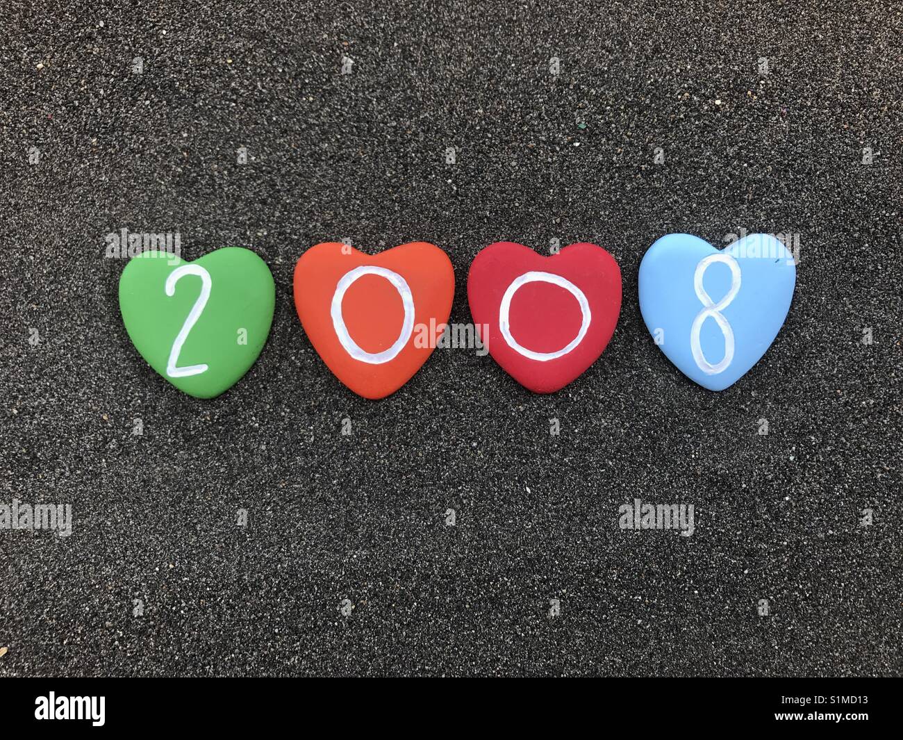 2008 year with colored heart stones over black volcanic sand - Smartphone Captured Stock Image