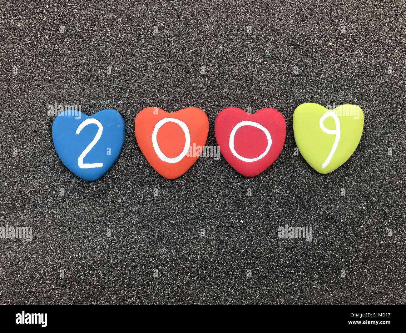 2009 year with colored heart stones over black volcanic sand - Smartphone Captured Stock Image