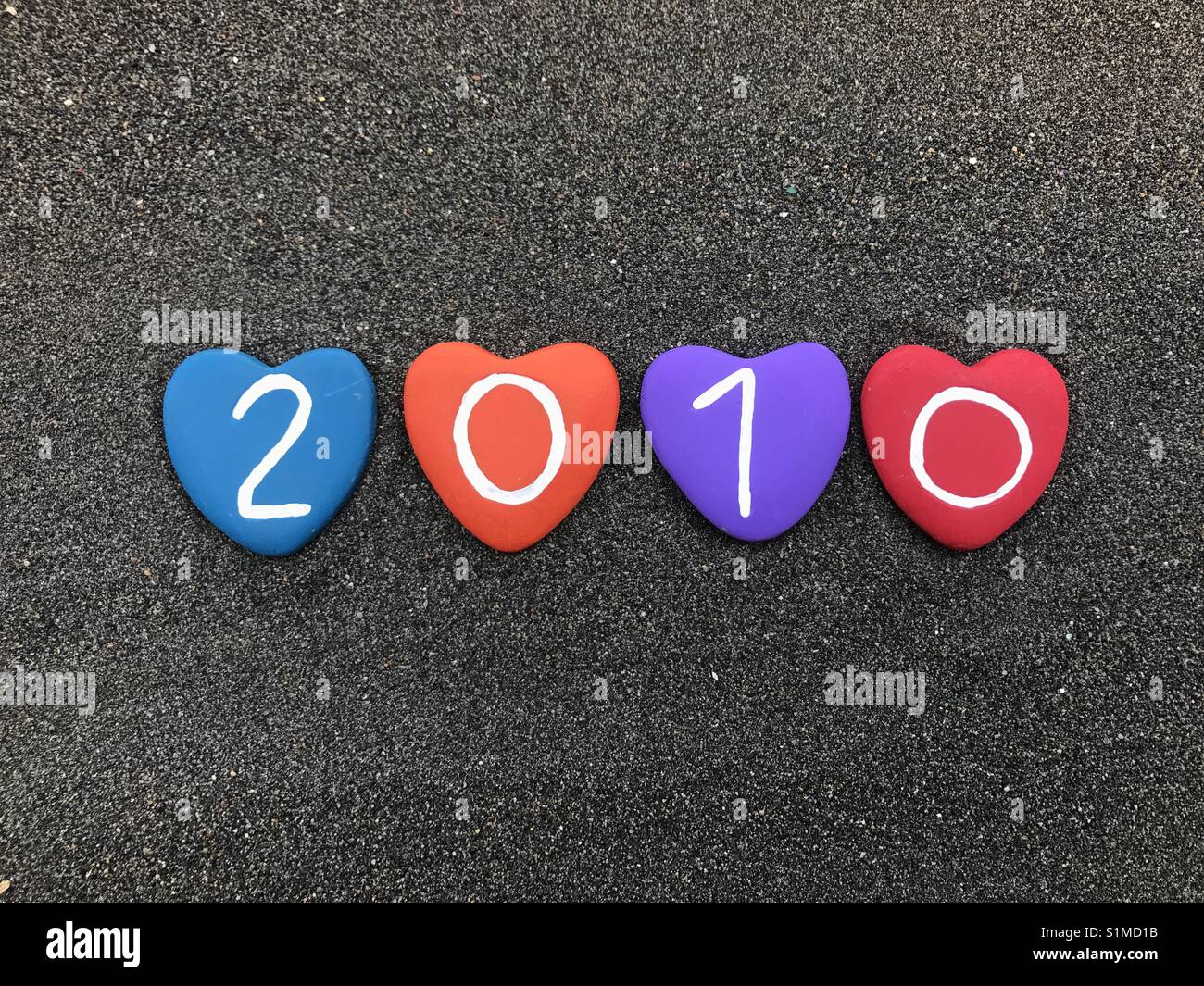 2010 year with colored heart stones over black volcanic sand - Smartphone Captured Stock Image