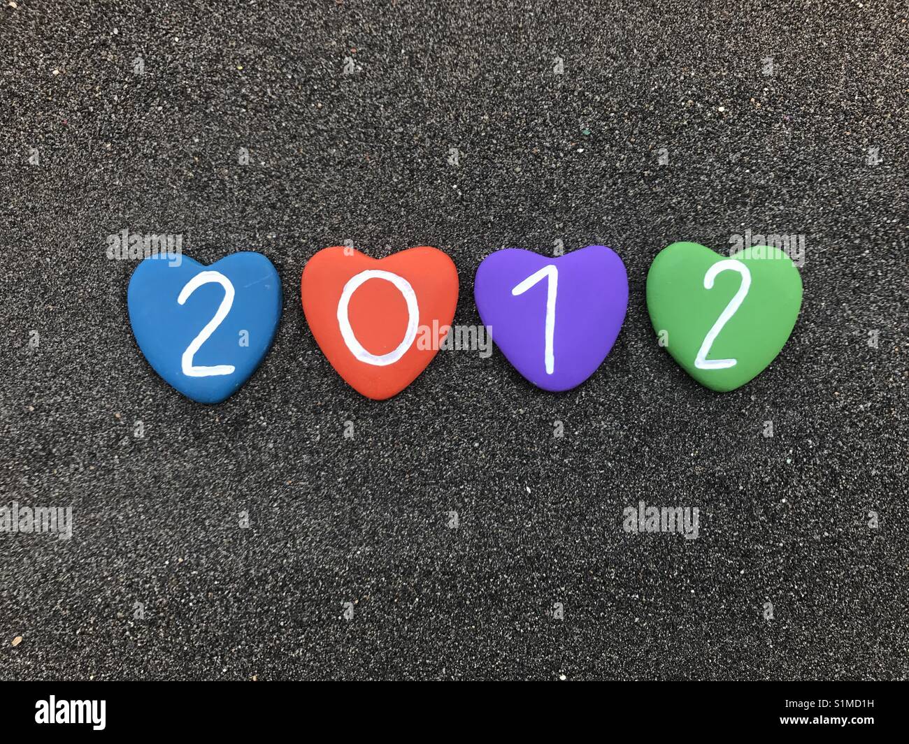 2012 year with colored heart stones over black volcanic sand - Smartphone Captured Stock Image