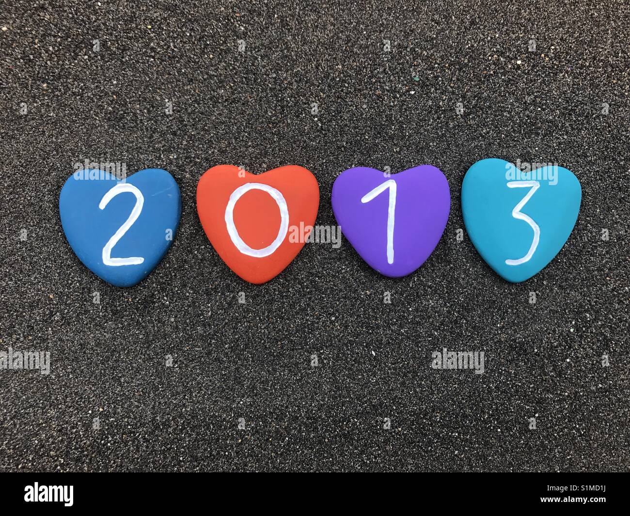 2013 year with colored heart stones over black volcanic sand - Smartphone Captured Stock Image