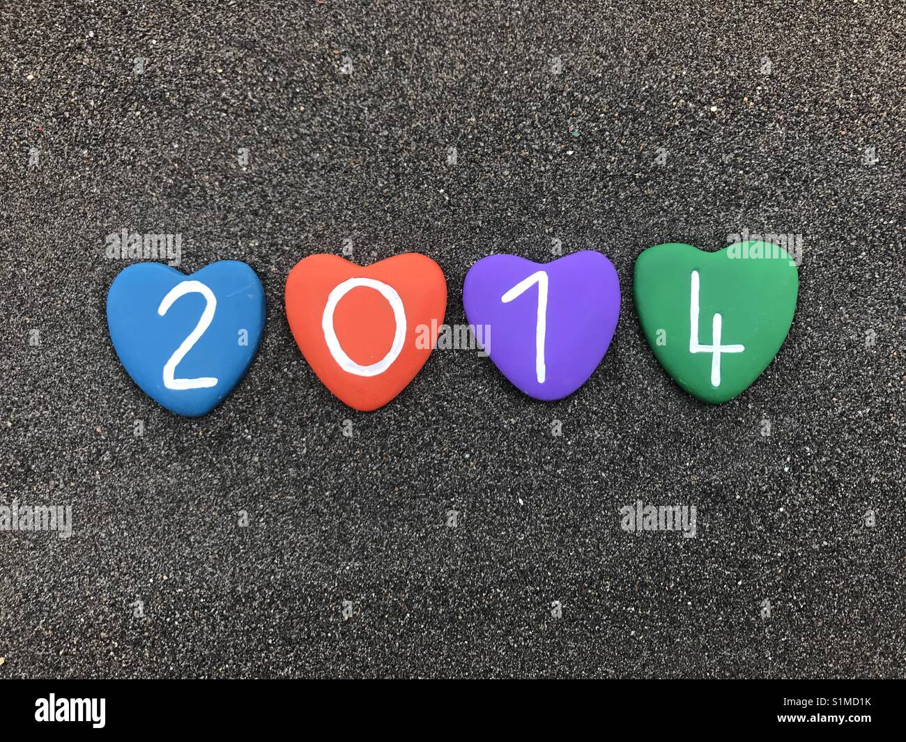 2014 year with colored heart stones over black volcanic sand - Smartphone Captured Stock Image