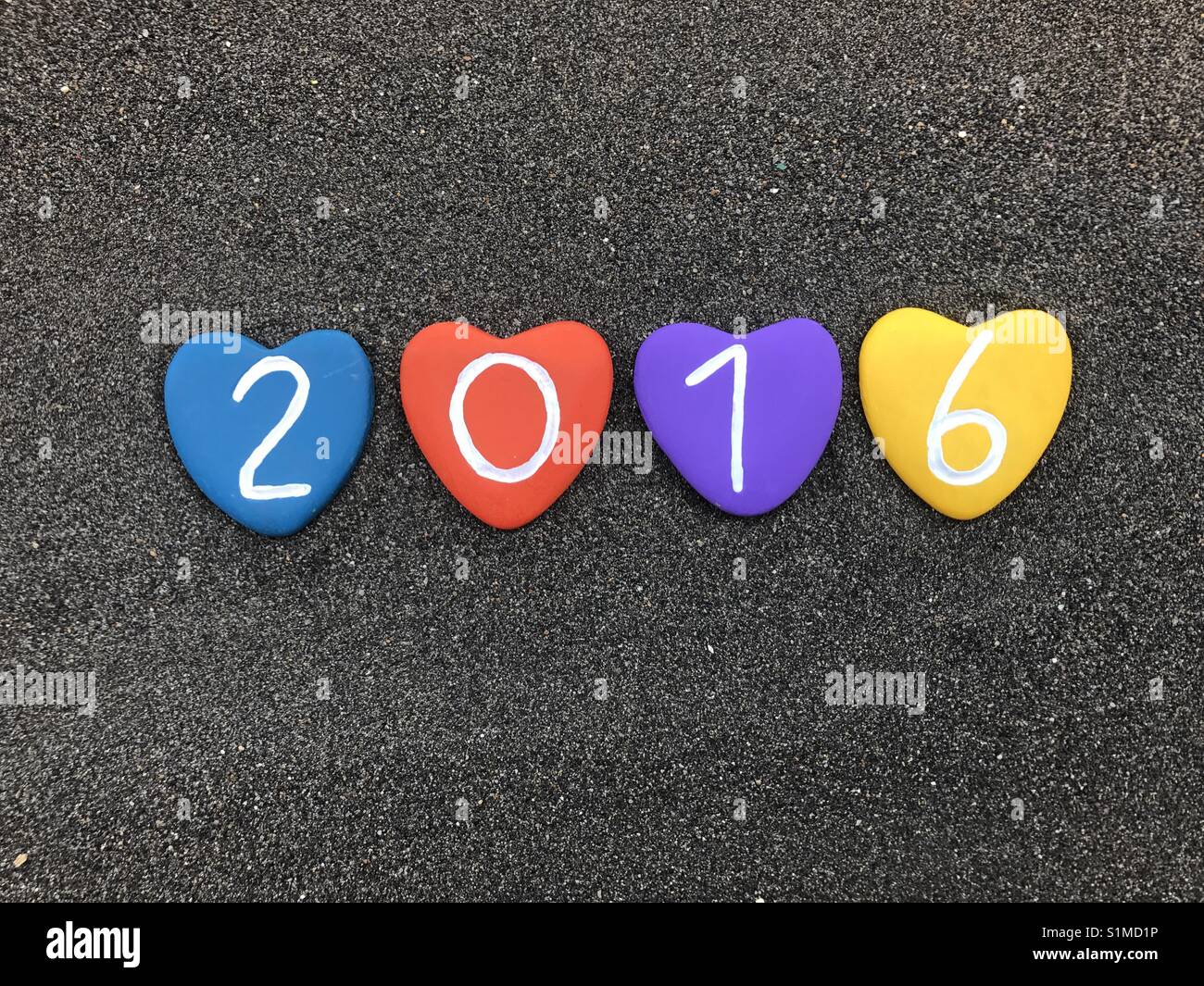 2016 year with colored heart stones over black volcanic sand - Smartphone Captured Stock Image